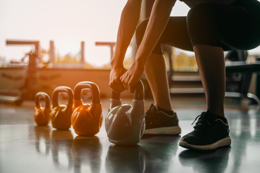 Woman in exercise gear standing in a row holding dumbbells during an exercise class at the gym
